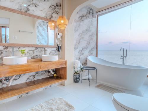 a bathroom with a tub and a window with the ocean at Sofia - Summer Coastal Suites in Bacnotan