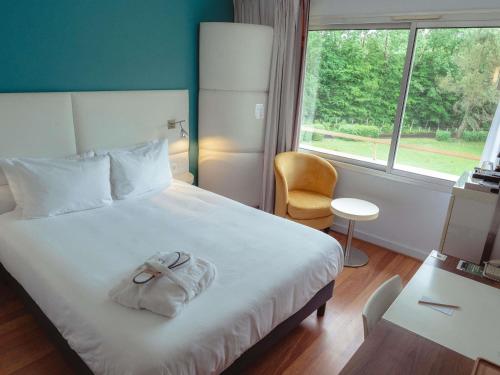 a bedroom with a bed with a towel on it at Mercure Brive in Ussac