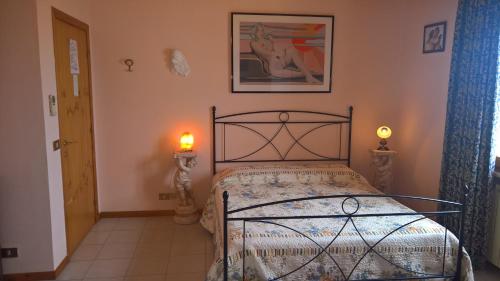 ein Schlafzimmer mit einem Bett mit einer Lampe und einem Bild an der Wand in der Unterkunft Azienda Agrituristica Piccolo Ranch in San Pietro