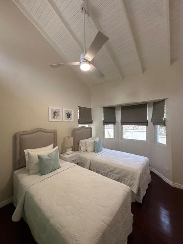 a bedroom with two beds and a ceiling fan at Casa Colibri in Saint James
