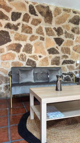 a couch in a living room with a stone wall at Alojamientos del Valle in Sotillo de la Adrada