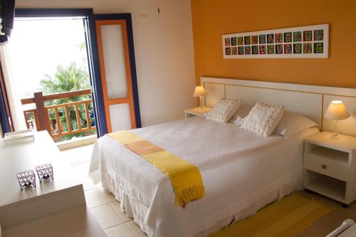 a bedroom with a white bed and a balcony at Pousada DiMari in Boicucanga