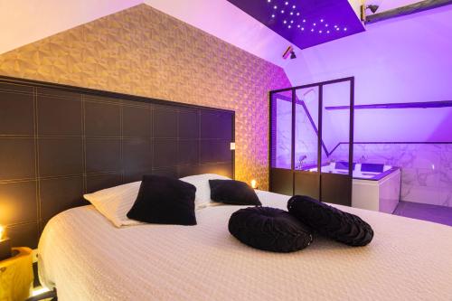 a bedroom with a large bed with two pillows on it at L'Intemporel Éclipse Suite Spa Privatif in Champagne-sur-Oise