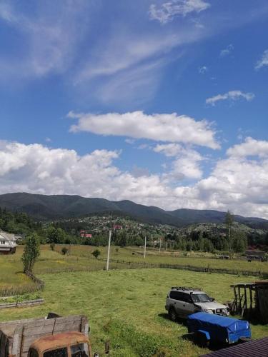 two cars parked in a field with mountains in the background at Форесок in Vorokhta