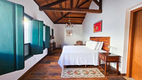 a bedroom with a white bed and a wooden floor at Pousada Casa de Salim in Lençóis