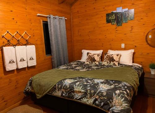 a bedroom with a bed in a wooden wall at Cabana Recanto dos Aparados in Cambará