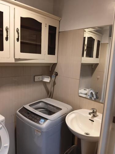 a small bathroom with a sink and a trash can at Shell Residences MOA Elegant Place in Manila