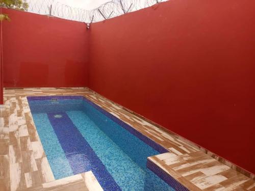 a swimming pool in a room with a red wall at CarteSurTable - Votre havre de paix aux portes de la ville - Villa haut standing in Yamoussoukro