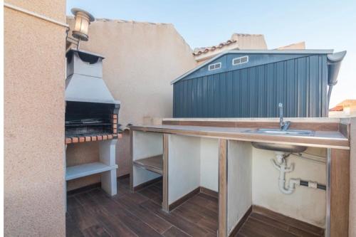 an outdoor kitchen with a sink and a stove at Bungalow en la Playa con Terraza Soleada, Jacuzzi, Solarium, Piscina comunitaria in Gran Alacant