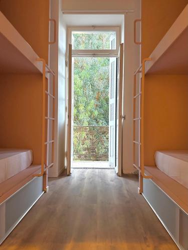 pusty pokój z dwoma łóżkami piętrowymi i otwartymi drzwiami w obiekcie Pink Pineapple Hostel w Atenach