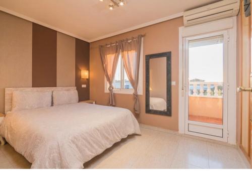 a bedroom with a bed and a large window at Bungalow en la Playa con Terraza Soleada, Jacuzzi, Solarium, Piscina comunitaria in Gran Alacant