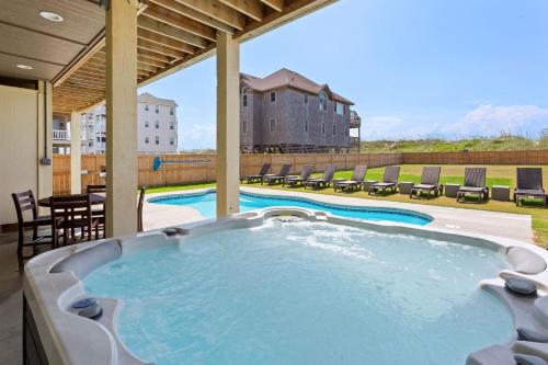a large hot tub on a patio with chairs at 8910 - Aquasition in Hatteras