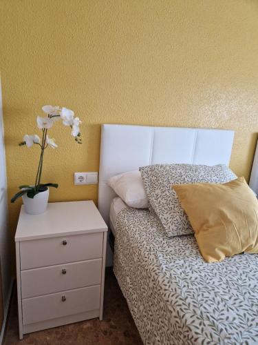 a bedroom with a bed with a vase of flowers on a night stand at Devesa Park in Playa de Gandia