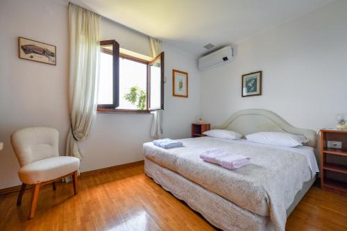 a bedroom with a bed and a chair and a window at House H-ELIOS in Lovran
