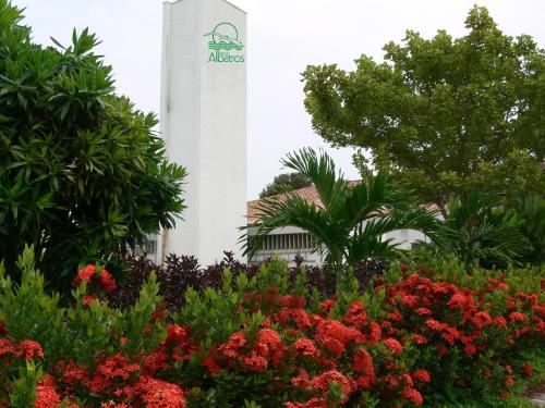 a clock tower behind a garden of flowers at Hotel Albatros in Espinal