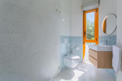 a bathroom with a toilet and a sink and a window at Maréa - Boutique Stay in Torre a Mare