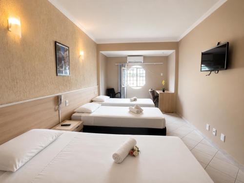 a hotel room with three beds and a flat screen tv at Hotel Econotel by Bsb Inn in Brasília