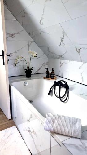 a white bathroom with a bath tub with flowers at Le Cosy Houdan in Goussainville