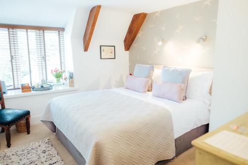 a bedroom with a white bed with pink pillows at The Cott Inn in Totnes
