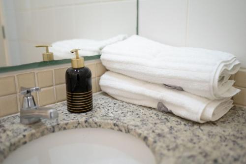 a bathroom counter with towels and a bottle of soap at Vossa Bossa Olimpia in Olímpia