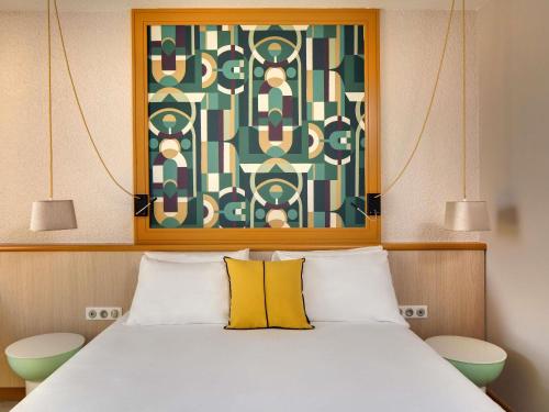 a bedroom with a bed with a painting above it at Mercure Vichy in Vichy