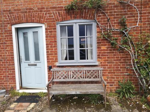 a wooden bench sitting in front of a brick building at Priory Cottage Castle Acre in Castle Acre
