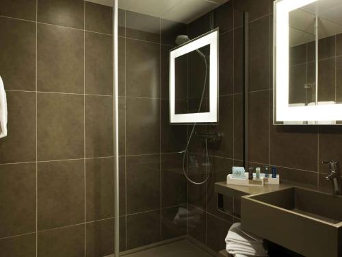 a bathroom with a shower and a sink and a mirror at Novotel Nottingham Derby in Long Eaton