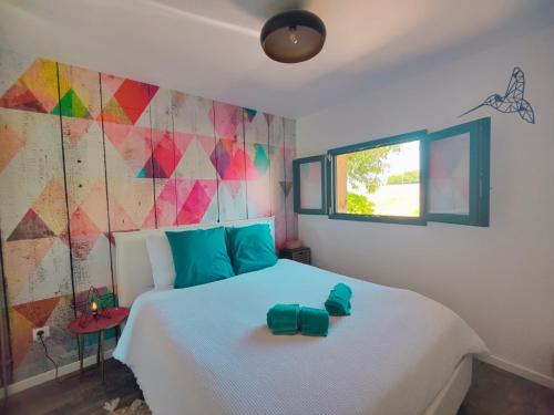 a bedroom with a white bed with a colorful wall at À la Volette - Cosy, Nature & Miel des Vosges in Plombières-les-Bains