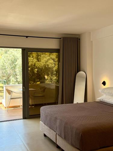 a bedroom with a bed and a balcony with a table at Skiathos Bliss Villa in Skiathos