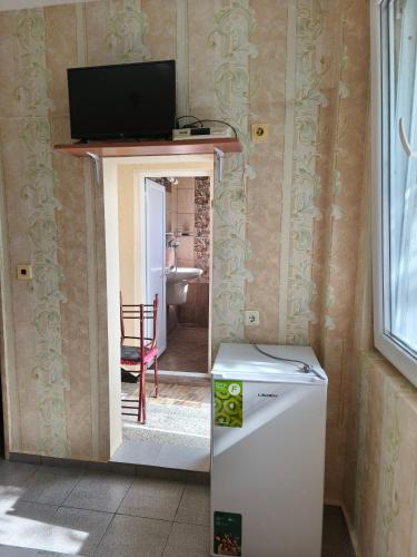 a room with a refrigerator and a television on a wall at Дом Колеви in Chernomorets
