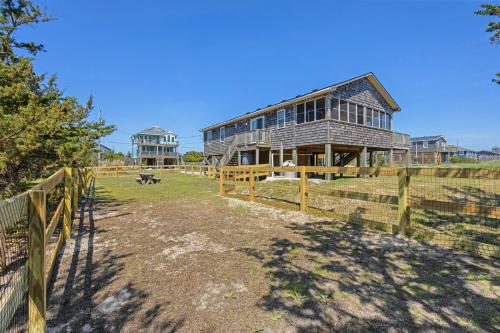 a barn with a fence in front of a house at 8055 - Down By The Dunes in Rodanthe