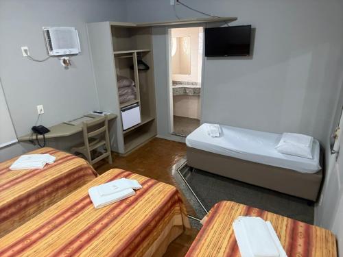 a small room with two beds and a television at Primum Palace Hotel in Dracena