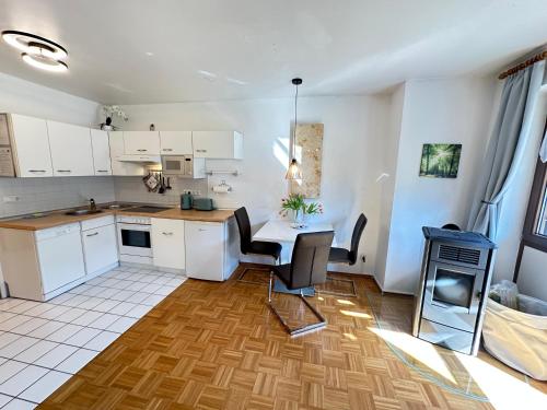 a kitchen with white cabinets and a table and chairs at Ferienwohnung mit Kamin - Hunde willkommen in Falkenstein