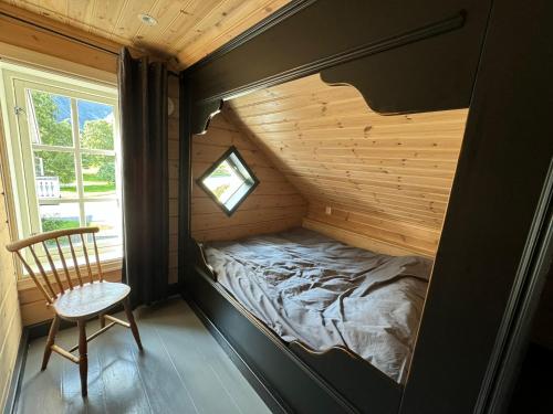 a bed in a small room with a chair and a window at Horgheim Boutique Lodge, Romsdalen in Åndalsnes