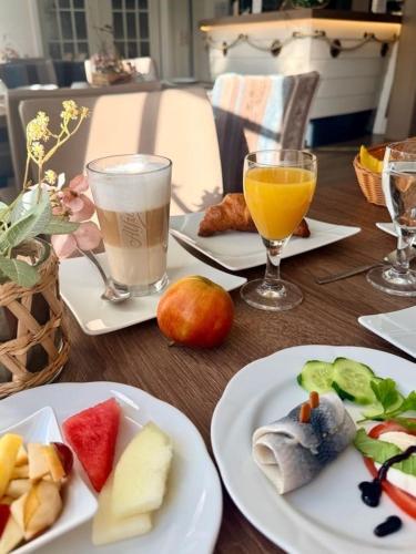 a wooden table with plates of food and glasses of juice at Hotel zur Seemöwe in Insel Poel