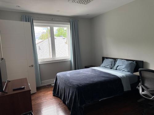 a bedroom with a bed and a window and a chair at Modern House in Toronto in Toronto