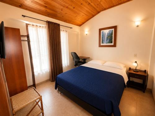 a bedroom with a blue bed and a desk at Hostal La Candelaria in Bogotá