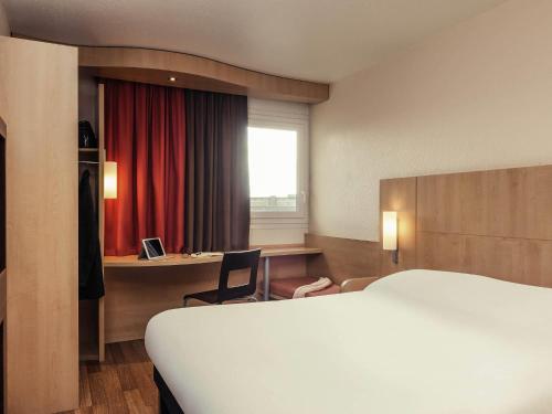 a hotel room with a bed and a desk at ibis Epinay sur Seine - Gennevilliers in Épinay-sur-Seine