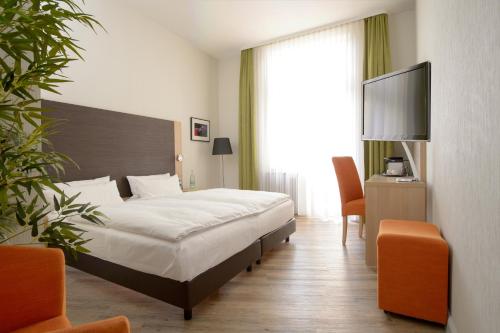 a hotel room with a couch, chair and a television at Apartmenthotel Kaiser Karl in Bonn
