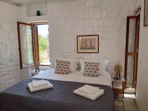 a white bedroom with a large bed with two pillows at Egina Home in Egina