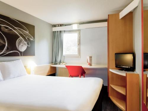 a hotel room with a bed and a red chair at ibis Lyon Nord in Dardilly
