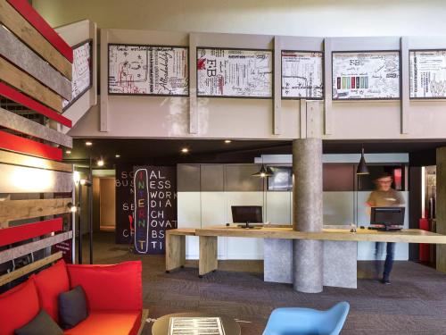 a lobby with a desk and a person in the background at ibis Saint-Nazaire - Trignac in Saint-Nazaire