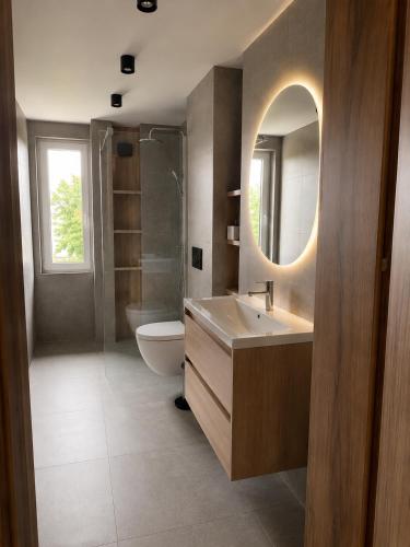 a bathroom with a sink and a toilet and a mirror at Apartamenty Sznurki in Sznurki