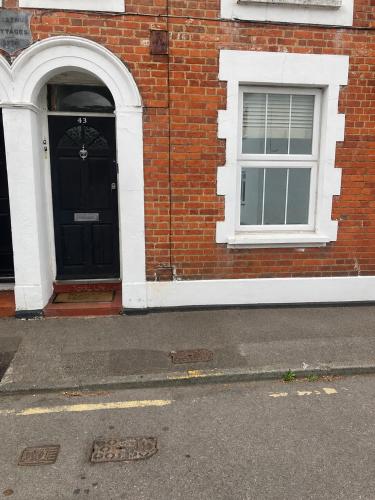 a brick building with a black door and two windows at Chestnut Villa in Epsom