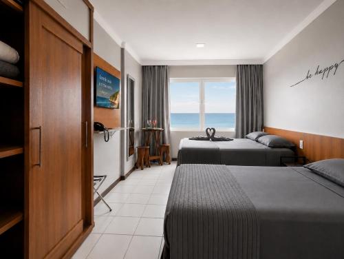 a hotel room with two beds and a window at Flat vista Mar -conforto e estilo em Ponta Negra-Natal in Natal