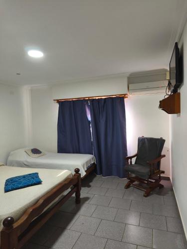 a room with two beds and a chair and a window at Tesoro Escondido in Santa Rosa