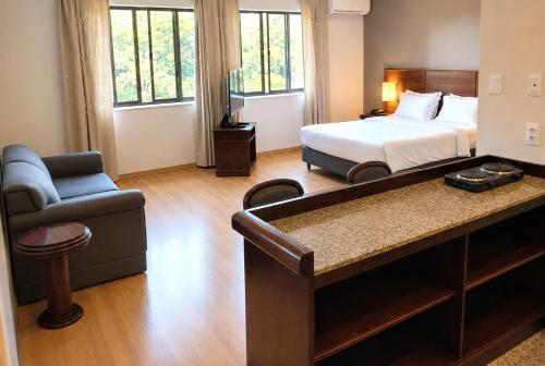 a bedroom with a bed and a couch and a chair at Apartamento no Hotel Prinz in Joinville