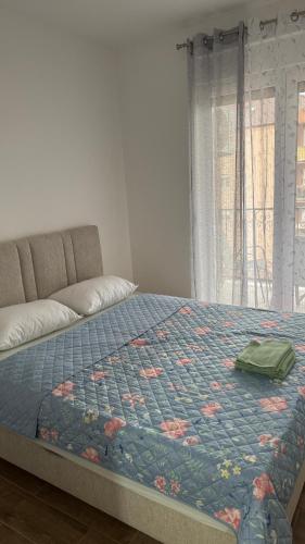 a bed with a blue comforter with a bag on it at Apartman 38 in Stara Pazova