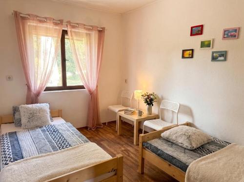 a bedroom with two beds and a table and a window at Chata Domaša - Monika in Holčíkovce