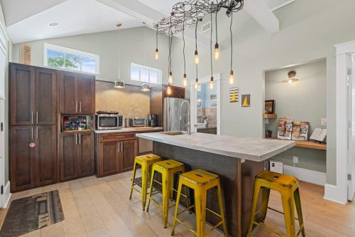 a kitchen with a large island with yellow stools at Riberia Columbus Cottage - Team Joseph Ellen in St. Augustine